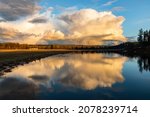 Small photo of A thunderstorm passes over the Snoqualmie Valley in Washington State, reflecting in Sikes Lake. White clouds rise high into the blue evening sky