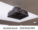 Small photo of A black overhead projector on ceiling in a conference room modern classroom color toned image.