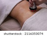 Small photo of procedure removing cellulite on female abdomen, cavitation belly massage. Ultrasonic massage for weight loss. Correction of female figure without surgical intervention. Closeup of the tummy.