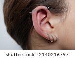Small photo of Stretched lobe piercing, grunge concept. Pierced woman ear with black plug tunnel. industrial and rook.