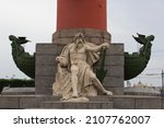 Small photo of SAINT PETERSBURG, RUSSIA 12.08.2021 god of sea and commerce sculpture on Rostral Column with ship prows decorations on the sides (architect - Jean-Francois Thomas de Thomon). Front view shot