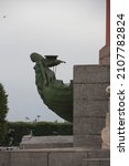 Small photo of SAINT PETERSBURG, RUSSIA 12.08.2021 bronze prow of a ship decoration of the bow with woman goddess figurehead on Rostral Column (architect - Jean-Francois Thomas de Thomon). Vertical side view shot