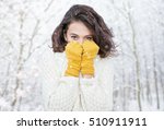 Beautiful natural young smiling brunette woman wearing knitted sweater and glove in the woods. Snowing snow winter concept.