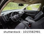 Dark car Interior - steering wheel, shift lever and dashboard. Car modern  inside. Front view on a background of nature in the rain.