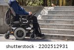 Small photo of Person with disability on electric wheelchair stopping at the bottom of inaccessible staircase, unable to reach the top