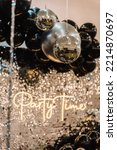Small photo of Disco ball. Happy New Year 2023. Bright glowing disco ball on photo booth with decor text party time. Light blur background for wedding or birthday. Zone, wall decorated black and silver balloons.