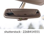 Car rearview mirror in automobile. Vehicle interior with rear view mirror and windshield - car salon concept. Auto dim button. Auto dimming button. Details interior closeup.