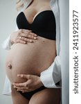 Small photo of Pregnancy motherhood procreation concept. Pregnant woman. Closeup belly of a woman. Female waiting for newborn baby. Young pregnant girl touching and holding her belly and caring about health indoors.