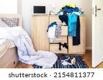 Small photo of mess in a teenager's room. Clothes are strewn across the chest of drawers, floor