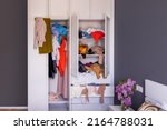 Small photo of Colored things lie in disarray in a white closet. Mess, organization of space