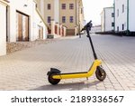 Yellow e-scooter in the old town on a summer day, per minute rent, copy space