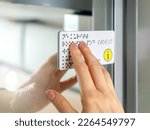 Person with blindness touches and reads with his hands the Braille text plate on the door of a train or bus. Close-up of fingers touching the relief of points in transport. Sightless, low vision.