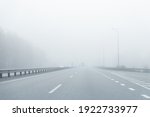 Driver POV of almost empty grey foggy misty rainy highway intercity road with low poor visibility on cold spring autumn morning. Seasonal bad rainy weather accident danger warning. car fog light