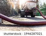Small photo of Close-up pipe hose of sewage truck car engine emptying home sewerage tank. Septic cleaning vacuum service and maintenance suburban countryside home. Suction vehicle cleaner machine pumping drainage