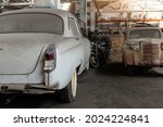 Many rusty abandoned forgotten antique oldtimer old car and motorcycles at junkyard factory storage warehouse indoors. Classic vintage retro vehicle detail garage workshop restore renovation station