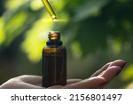 Close-up of drop dispensing biological and organic herbal pharmaceutical plant oil into jar, macro.