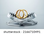 Small photo of Wedding rings in a bear trap, close-up. The concept of love, relationship, addiction, marriage, separation, heartache. 3D render, 3D illustration