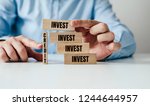 Small photo of Investing and borrowing. Wooden blocks jigsaw stacked on top of each other with the inscription Invest. Business and finance concept, investing with the help of credit. The man is indebted to invest.