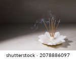 Small photo of Smoke from burning incense sticks standing on lotus incense holder