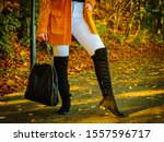 Unrecognizable woman wearing long orange warm cardigan sweater. Autumnal fashion, autumn season styled outfits. Female having a walk in park