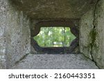 Small photo of View through shooting manhole to the outside. An old fortification fragment from the First World War, made from concrete with a lope hole - the small opening through which fired with a machine gunner.