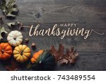 Happy Thanksgiving greeting text with colorful pumpkins, squash and leaves over dark wooden background
