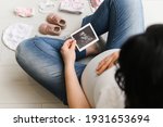 Pregnant woman enjoying future motherhood with her baby's first ultrasound photo, top view with free space