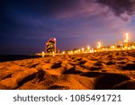 Small photo of A picture taken from a low down angle of the beach in Barcelona, Spain at night just after a storm had passed. The sand in the immediate foreground is in focus and creates empty space for text overlay