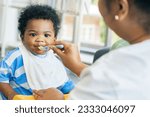 Small photo of Mother raising take care an African-American Thai son feeds him simple and nutritious lunch : Portrait baby boy who enjoys looking at the camera eating food relishing and gluttonous .
