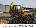 Small photo of Yellow wheel loader Excavator machine working at construction site with gravel. Preparing of the fundament for a asphalting. Road construction site. Building of a parking.