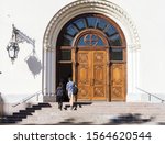 two people, man and a woman (view from the back) climb the steps to the open door of the church holding hands.  Entrance to the Lutheran Church in the center of St. Petersburg.(Petrikirche)