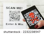 QR code scam concept - scanning a QR code can lead to phishing websites or malware apps. A female scanning a fraudulent QR code that is way for cons to steal your passwords and other valuable info
