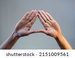Small photo of hand gesture, triangle shape, male doing triangle hand gesture on toned background, isolated. illuminati
