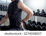 Small photo of Sport man feeling lower back pain or spine pain after doing weight training exercise in fitness gym. Male athlete suffering from sport injury symptom.