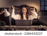Small photo of Woman at her laptop, hair in disarray, reflects stress and agitation faced during a demanding work session at home