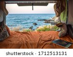 beautiful mediterranean view from a cozy bohemian camper van interior. Unmade bed, pillows, van life theme. Vanlife lifestyle and travel concept/ young people traveling with camper/ restored vehicle