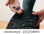 Small photo of Renew Lost studs. Hand with repair steal studs. Worn tire tread, winter studded tire - wheel repair service. Old winter studded tire close up.