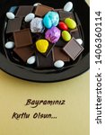 Small photo of Chocolate madlen and almond candies in black plate.Happy Feast greeting message writting under in Turkish