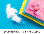 Laundry concept. Clean linen and orchid near washing powder on blue background top view