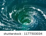 High angle view of a powerful whirlpool at the surface of green water with foam.