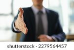 Small photo of Businessman in suit extending his hand for handshake to partner at work in office closeup