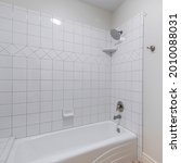 Small photo of Square frame Interior of a bathroom with toilet bowl and alcove bathtub shower combo with tiles