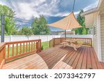 Wooden deck with a sunshade over the table with bench seats
