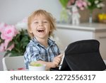 Small photo of Little toddler child, blond boy, licking lollipop at home while watching movie on tablet