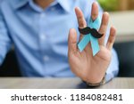 Small photo of Prostate Cancer Awareness, Man hand holding light Blue Ribbon with mustache for supporting people living and illness. Men Healthcare and World cancer day concept