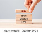 Businessman hand placing or pulling wooden block with Risk text over High Medium and Low. planning, risk Management, economic, finance and corporate Concepts