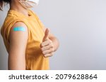 Small photo of woman showing Thumb sign with bandage after receiving covid 19 vaccine. Vaccination, herd immunity, side effect, booster dose, vaccine passport and Coronavirus pandemic