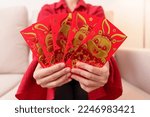 Small photo of woman holding Chinese red envelope with golden rabbit and blessing word, money gift for happy Lunar New Year holiday. Chinese sentence means happiness, healthy, Lucky and Wealthy