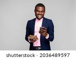 young african businessman wearing a suit, holding a lot of money and using his phone