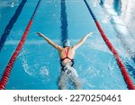 Small photo of Successful female swimmer swimming in the pool. A professional athlete is determined to win the championship
